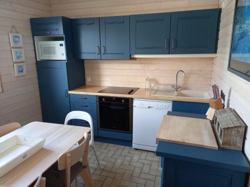 a kitchen with blue cabinets and a sink and a table at Sous les toits de Saint-Enogat in Dinard