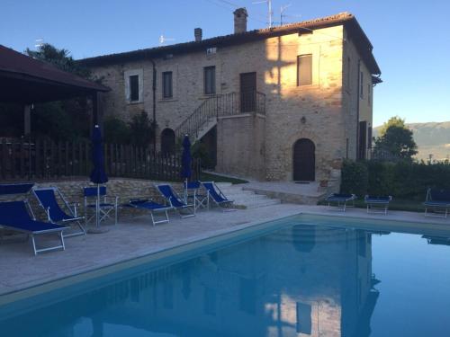 una casa y una piscina con sillas y un edificio en B&B La Noce, en Montefalco