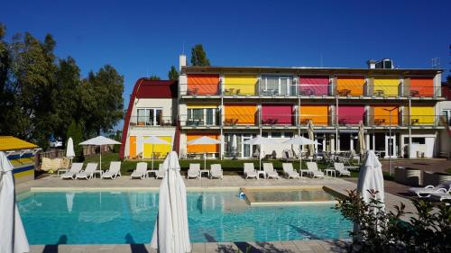 a hotel with a swimming pool and chairs and umbrellas at Colors Holiday Hotel in Siófok
