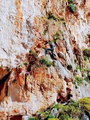 a person rappelling off of a mountain cliff at Villa Corallina Relais & Climbing Center in San Vito lo Capo