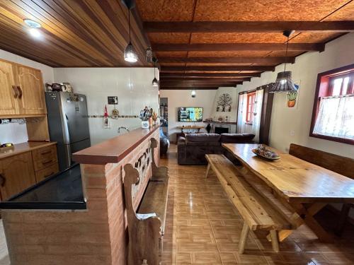 cocina y sala de estar con mesa de madera en Recanto Luar en Camanducaia
