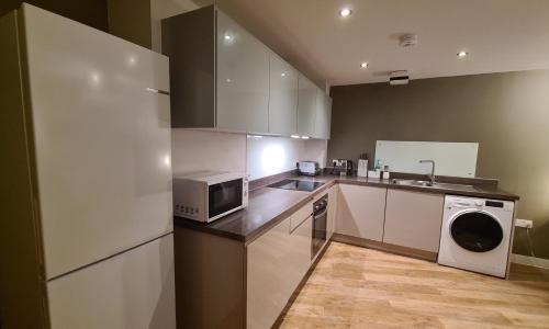a kitchen with a microwave refrigerator and a sink at Modern One Bedroom Apartment in Cardiff Bay in Cardiff