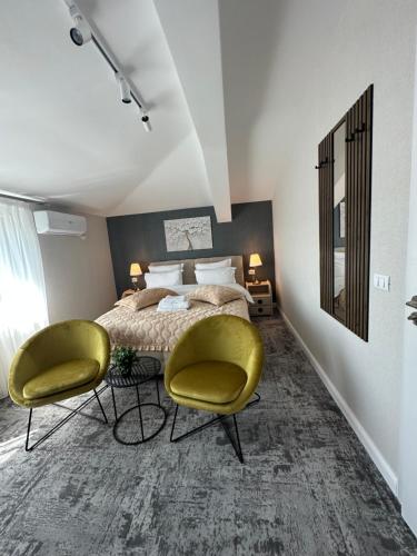 a bedroom with a bed and two yellow chairs at Complex Rediu 54 Luxury Apartaments in Iaşi