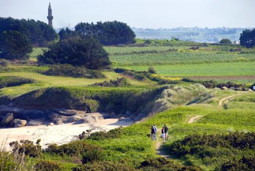 two people walking down a dirt path in a field at Hôtel La Résidence des Artistes in Roscoff