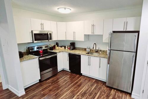 a kitchen with white cabinets and a stainless steel refrigerator at The Lofts on Clematis 206 Downtown West Palm Beach in West Palm Beach
