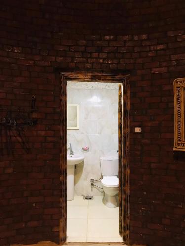 a brick bathroom with a toilet and a sink at Gazrashek Siwa Hot spring& trips Haven in Siwa