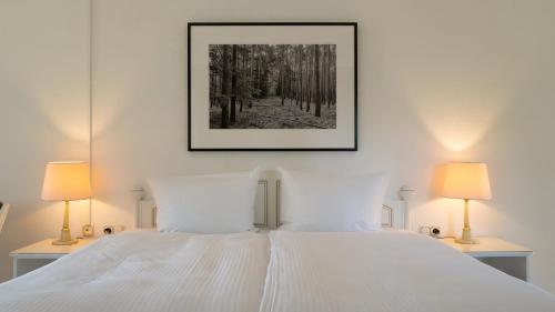 Un dormitorio con una cama blanca con dos lámparas. en nook Lakehouse, en Bad Saarow