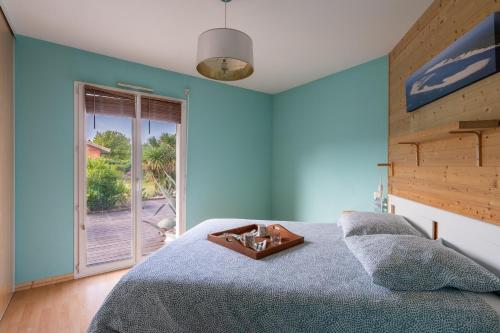 niebieska sypialnia z łóżkiem i oknem w obiekcie Chemin de l'Ombriere - Entre Bordeaux et le Bassin dArcachon w mieście Saint-Jean-dʼIllac