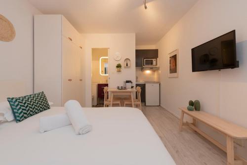une chambre avec un grand lit blanc et une cuisine dans l'établissement Le Roseau Toulousain, à Toulouse