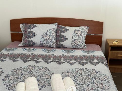 Bett mit einem Kopfteil aus Holz und 2 Kissen in der Unterkunft Apartments Airport Golubovci in Podgorica
