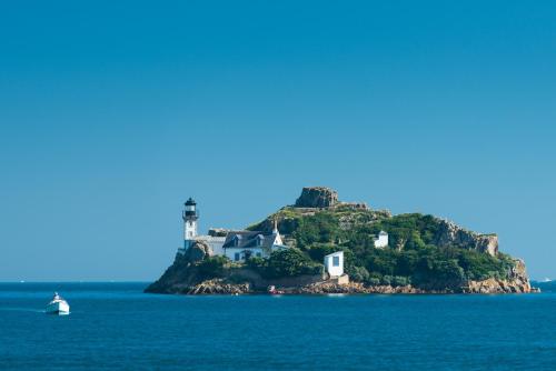 a small island in the water with a lighthouse at Hôtel La Résidence des Artistes in Roscoff