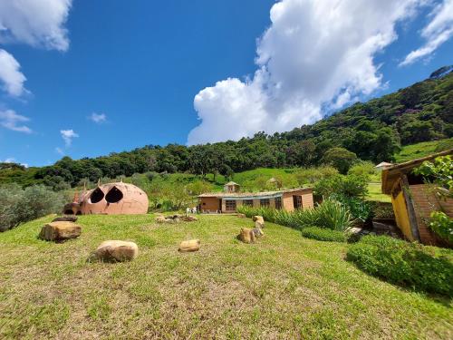 une maison dans un champ avec des rochers dans l'herbe dans l'établissement Espaço Lua Branca, à Baependi