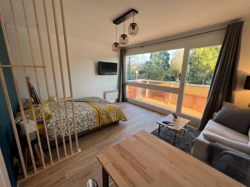 a bedroom with a bed and a large window at Studio - La parenthèse Valognaise in Valognes