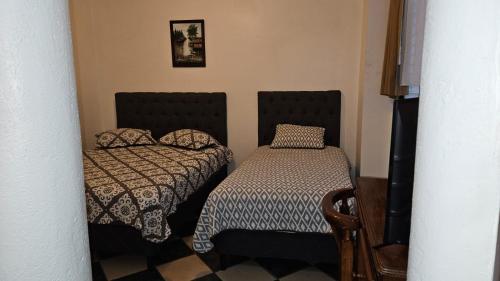 a small room with two beds and a table at Hotel Valladolid in Heredia