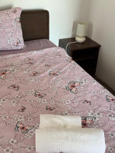 a bed with a pink comforter and a pillow at Apartments Airport Golubovci in Podgorica