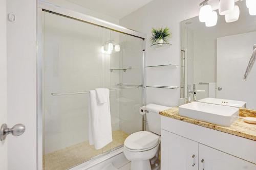 a white bathroom with a toilet and a sink at Coconut Bay Villas #116 in George Town