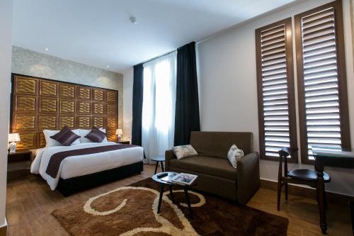 فندق Belllo JB Central في جوهور باهرو: غرفة نوم بسرير واريكة وكرسي