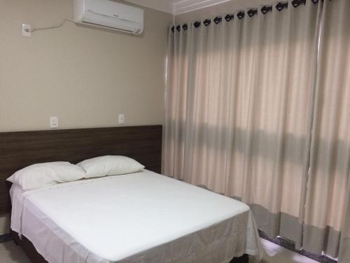 a bedroom with a white bed and a window at Hotel Mascarello in Planalto