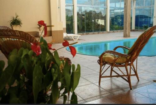 a pool with two chairs and a potted plant next to it at Hotel Mascarello in Planalto