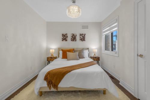 a white bedroom with a large bed with orange pillows at Luxury 6 Bedroom - 4 Bathroom Detached Retreat Brampton / Mississauga Border in Brampton