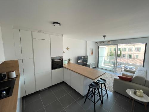 une cuisine avec des armoires blanches, une table et un canapé dans l'établissement Cannes, appartement avec parking+terrasse, Croisette à pied!, à Cannes