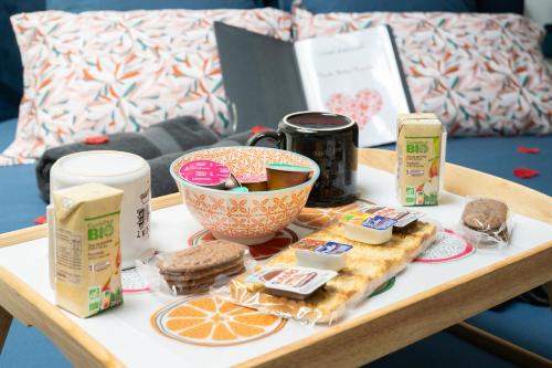 una mesa con una bandeja de comida y un plato de comida en L'Escale Balnéo'Romantique - Loveroom - Jacuzzi & Petit déjeuner, en Villiers-sur-Marne