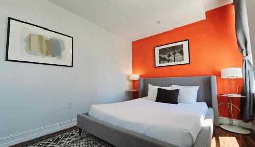 a bedroom with a bed with an orange wall at The Lofts on Clematis 407 Downtown West Palm Beach in West Palm Beach