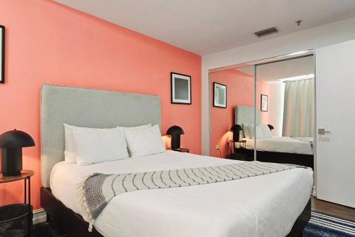 1 dormitorio con 1 cama grande y pared de color naranja en The Lofts on Clematis 504 Downtown West Palm Beach, en West Palm Beach