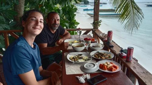 mężczyzna i kobieta siedzący przy stole z jedzeniem w obiekcie Yohana Cottage w mieście Tual