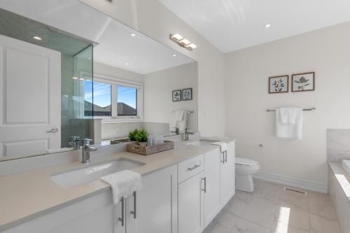 a white bathroom with a sink and a toilet at Luxury 6 Bedroom - 4 Bathroom Detached Retreat Brampton / Mississauga Border in Brampton