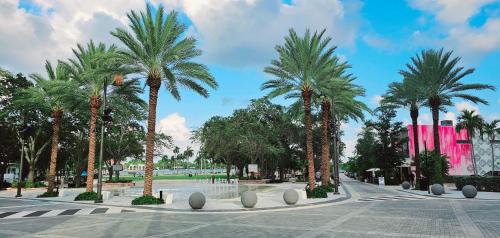 a courtyard with palm trees and a pink building at The Lofts on Clematis 508 Downtown West Palm Beach in West Palm Beach