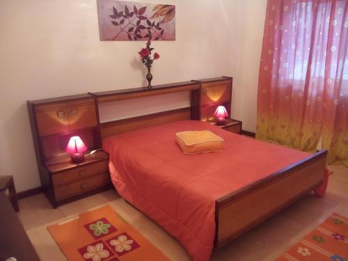 a bedroom with a bed with red sheets and two lamps at Apartamento Aracelli in Ermesinde