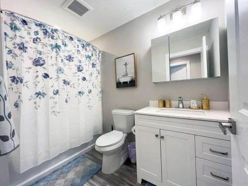 a bathroom with a toilet and a sink and a shower curtain at Brand New Build Cozy Private 3br2ba Home in South Euclid