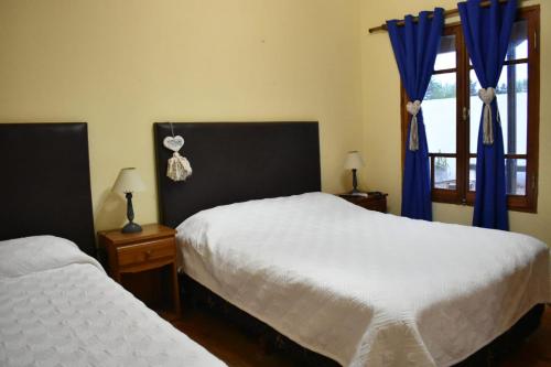 a bedroom with two beds and a window with blue curtains at El Colonial in Colón