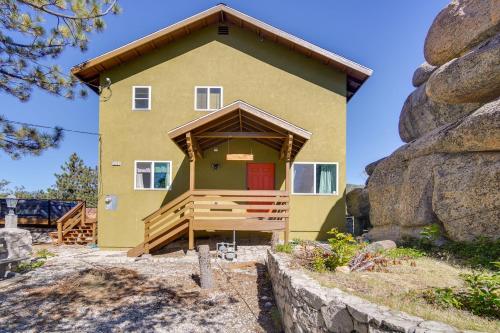 a yellow house with a red door and a rock at Running Springs Cabin with Spacious Deck and Hot Tub! in Running Springs
