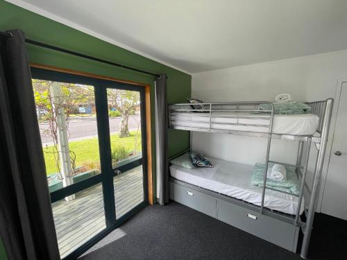 - une chambre avec des lits superposés et une porte donnant sur un balcon dans l'établissement Peppertree Lodge & Backpackers, à Paihia
