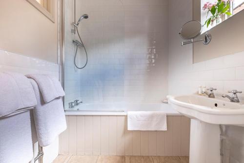 a white bathroom with a shower and a sink at The Ship At Dunwich in Dunwich