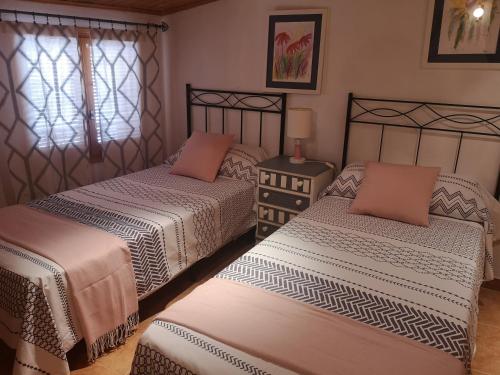 ein Schlafzimmer mit 2 Betten und einem Tisch mit einer Lampe in der Unterkunft Casa Dolors in Ossó de Sió