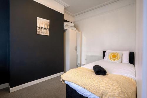 een slaapkamer met een bed met een muur met zwarte accenten bij Cozy 4-Bedroom in Coventry: Your Home Away From Home in Coventry