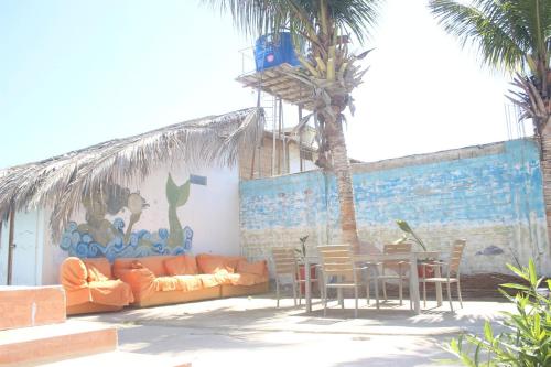 ピウラにあるÁngeles del Marのソファ、テーブル、ヤシの木があるパティオ