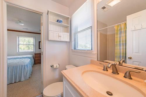 een badkamer met een wastafel en een toilet en een slaapkamer bij Bowen in Duck