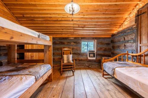 a log cabin bedroom with two beds and a chair at New! Charming Cabin in Colorado National Forest in Lake George