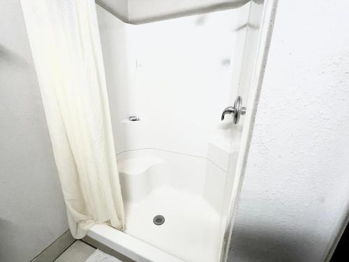 baño con ducha y puerta blanca en Azure Sky Motel, en Fort Scott