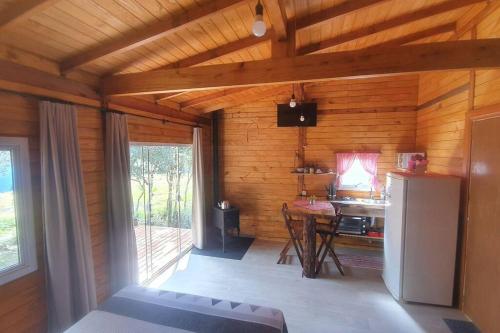 a room with a kitchen with a table and a refrigerator at Cabana no alto do morro in Nova Petrópolis