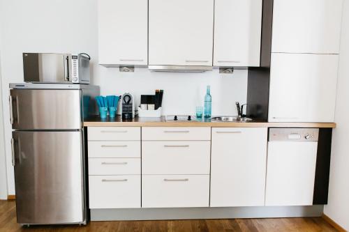 a kitchen with white cabinets and a stainless steel refrigerator at Home Sweet Apartments - A cozy welcome in Vienna