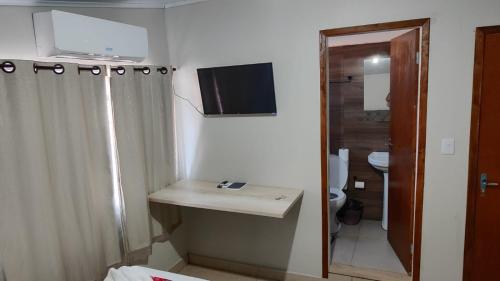 a bathroom with a toilet and a television on the wall at Royal Hotel in Dourados