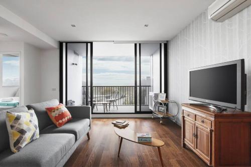 a living room with a couch and a flat screen tv at Urban Oasis in the Heart of Richmond Cultural Hub in Melbourne