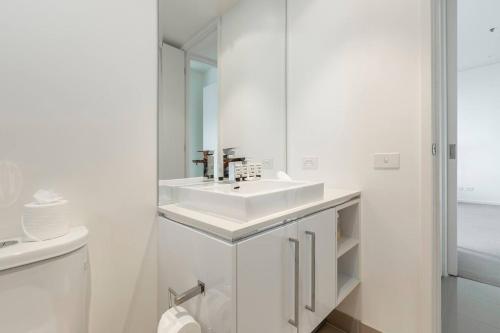 uma casa de banho branca com um lavatório e um espelho em Light, Elevated Living near Queen Victoria Market em Melbourne