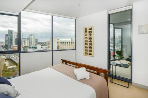 1 dormitorio con 1 cama y ventanas grandes en Backpackers' Delight with Sprawling City Views en Melbourne