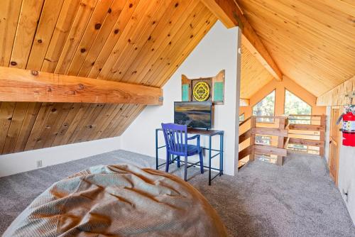 a bedroom with wooden ceilings and a blue chair and a table at Treehouse On Rainbow - A newly remodeled cabin perfect for a mountain getaway in Big Bear City